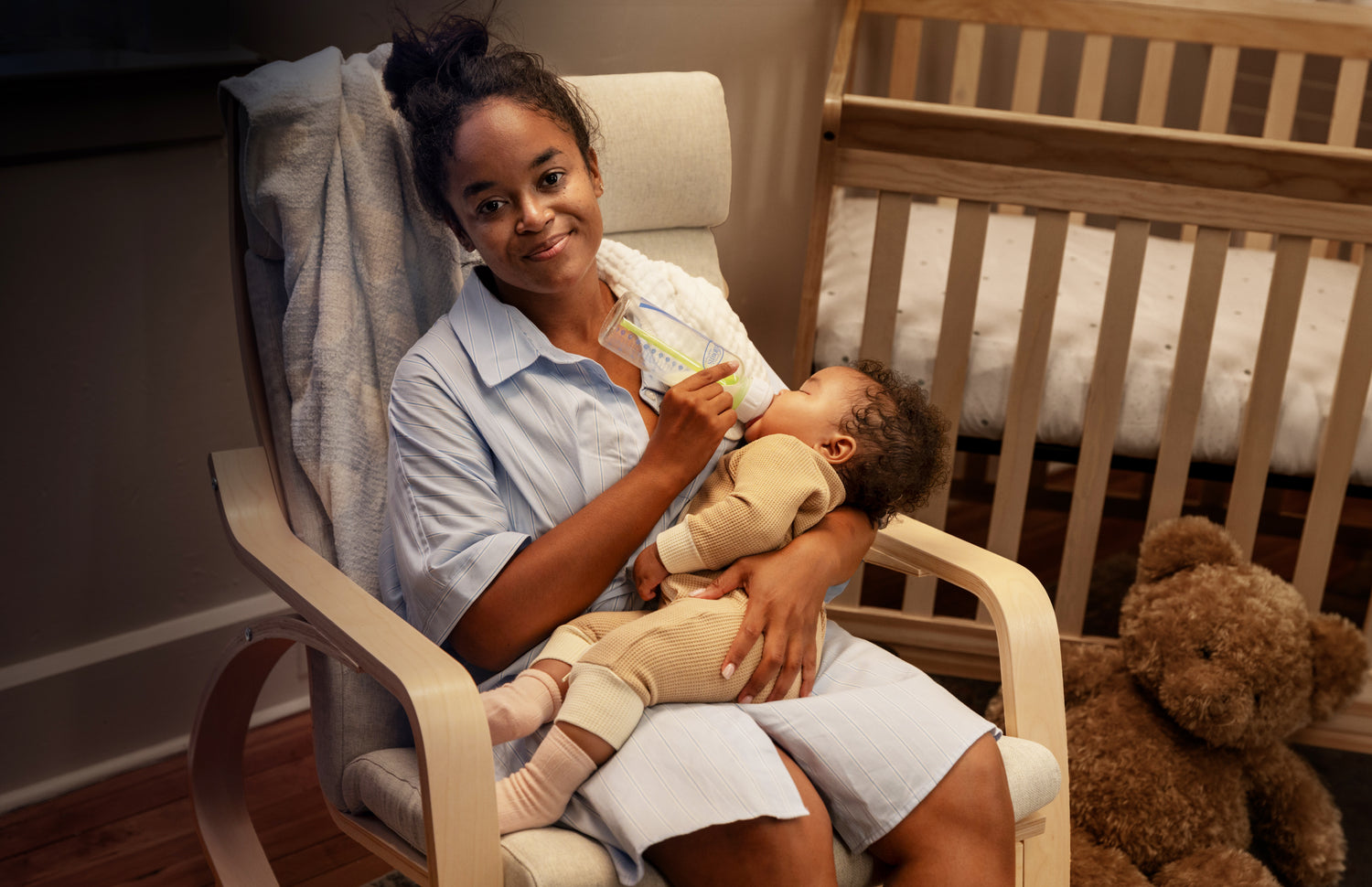 Mom feeding baby with Dr. Brown's bottle at night in nursery